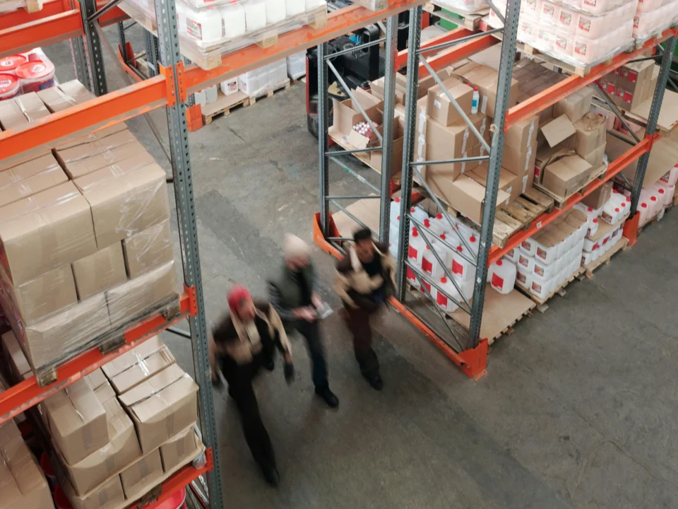 FLEX. workers walking among shelves in a modern fulfillment warehouse.